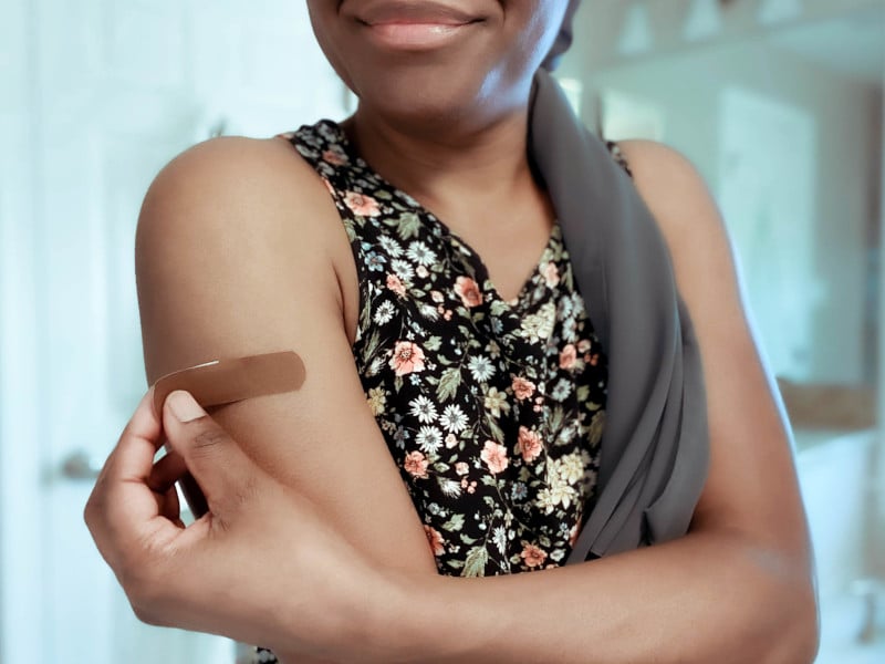 image of a person applying a small bandage to a wound on their upper arm