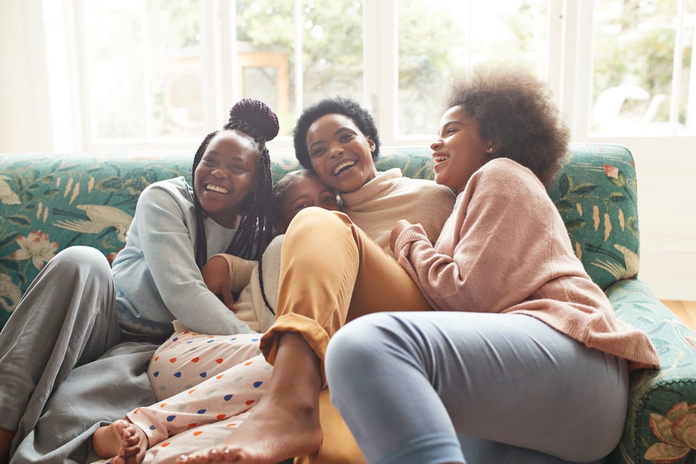 four women sitting on a couch together and laughing