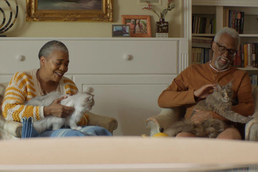 Couple sitting in the living room, each cradling a cat in their lap